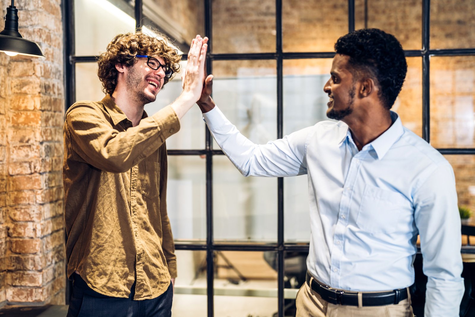 Un moment de complicité professionnelle : deux hommes d'affaires échangent un 'high-five' pour célébrer un succès, témoignant de la bonne entente et de l'esprit d'équipe.