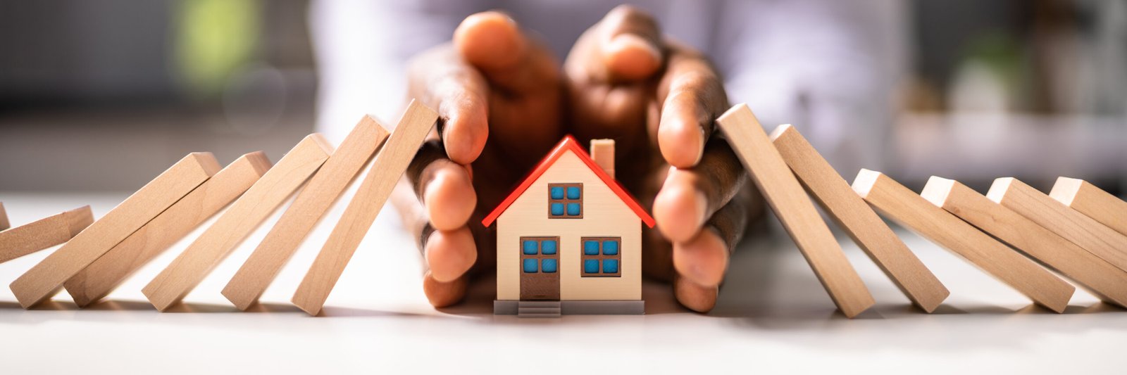 Une personne protégeant une petite maison avec ses mains, une métaphore puissante pour l'assurance et la sécurité dans le secteur immobilier.