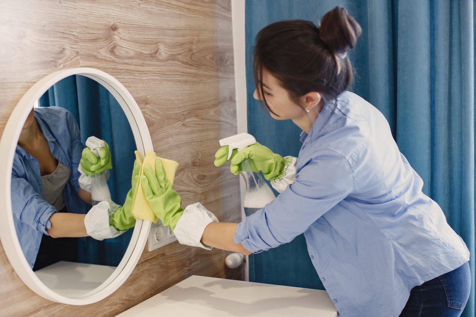 Une professionnelle nettoyant un miroir avec attention, démontrant le standard élevé de propreté chez Hexuvium.